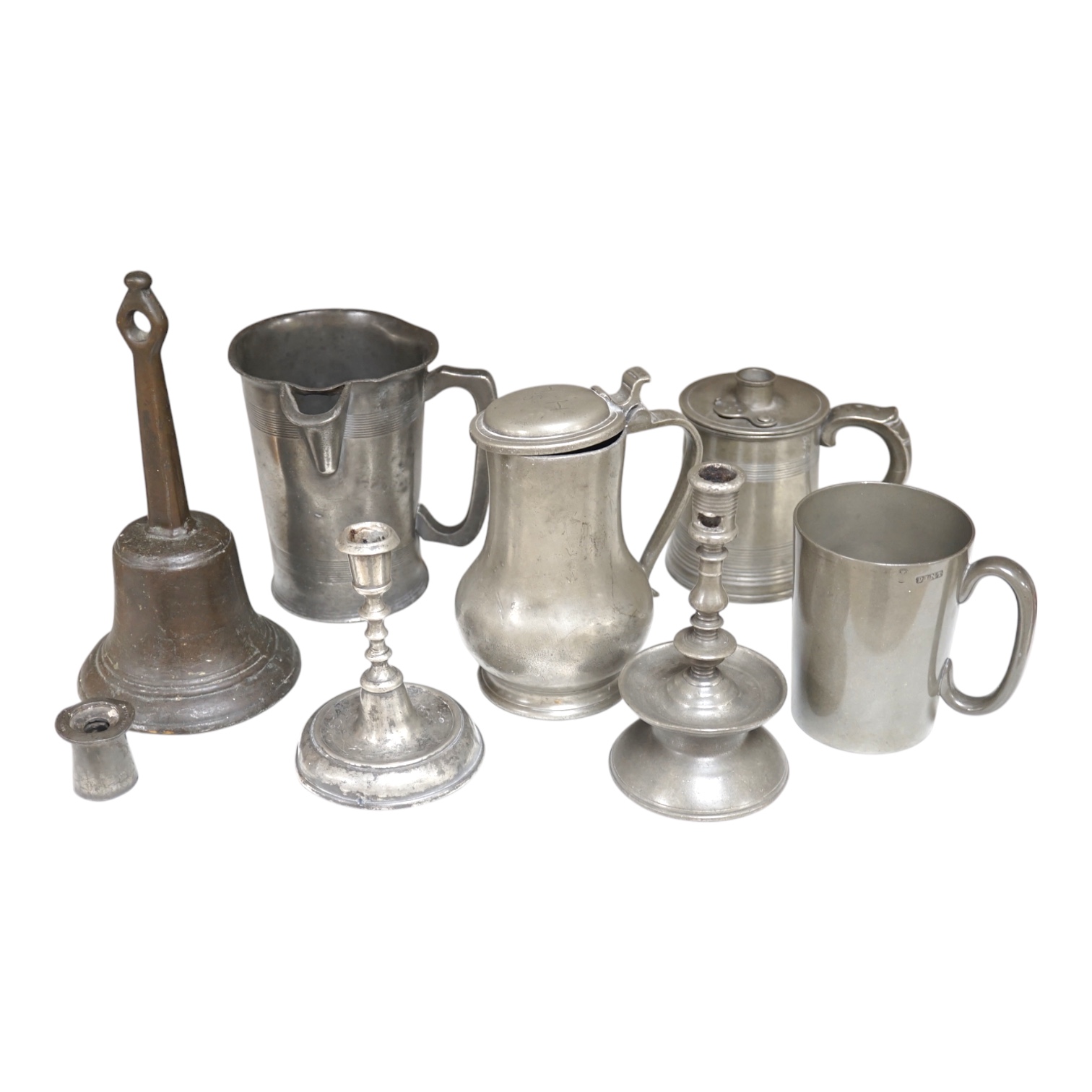 Six items of 18th century and later pewter including a jug, candlesticks, a pint measure, and a bronze hand bell, 24cm high. Condition - fair.